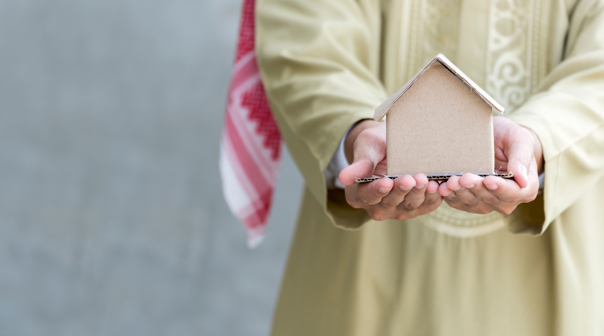 Arab man real estate agent holding house model in hands. Real estate concept